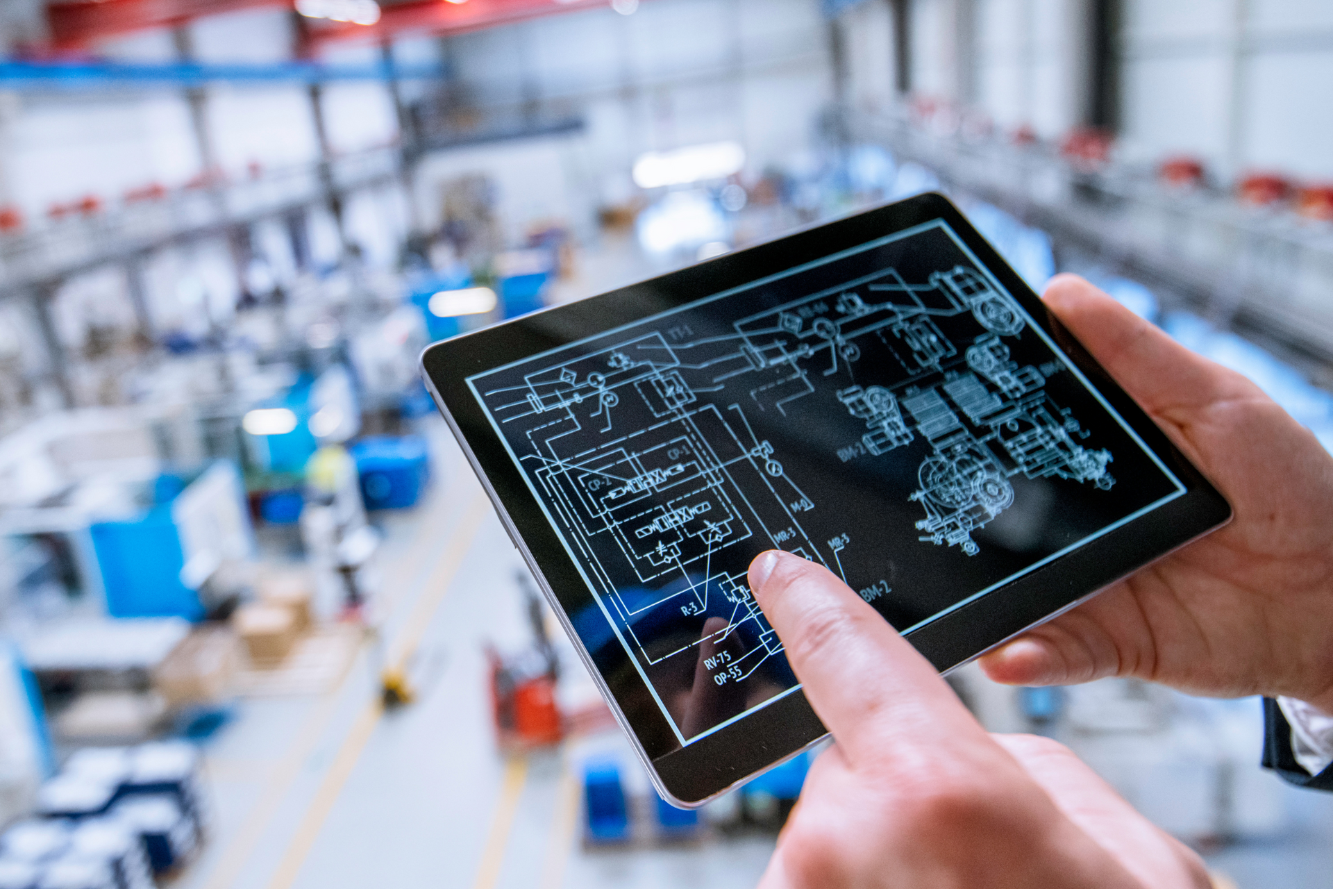 a person is holding a tablet with a blueprint on it in a factory .