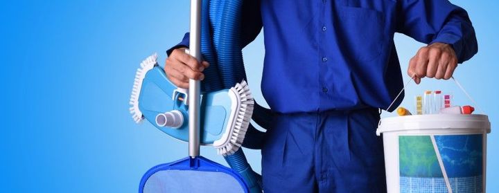 Person in blue uniform holding cleaning tools and a bucket against a blue background