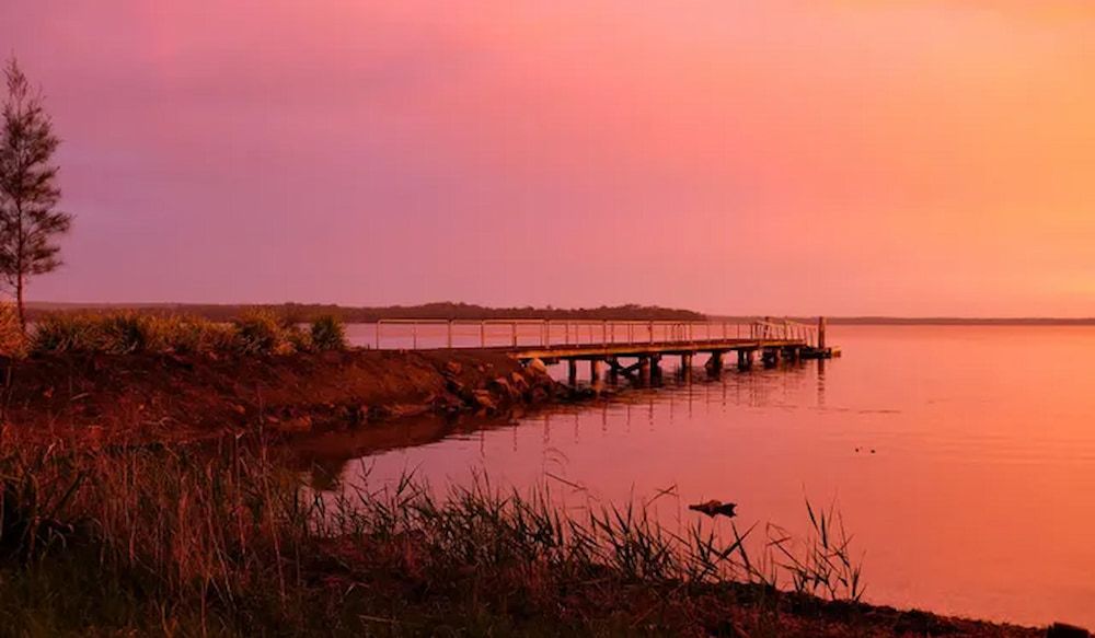 A Sunset Over A Lake With A Dock In The Foreground — Mike's Tree Services In Saint Georges Basin, NSW