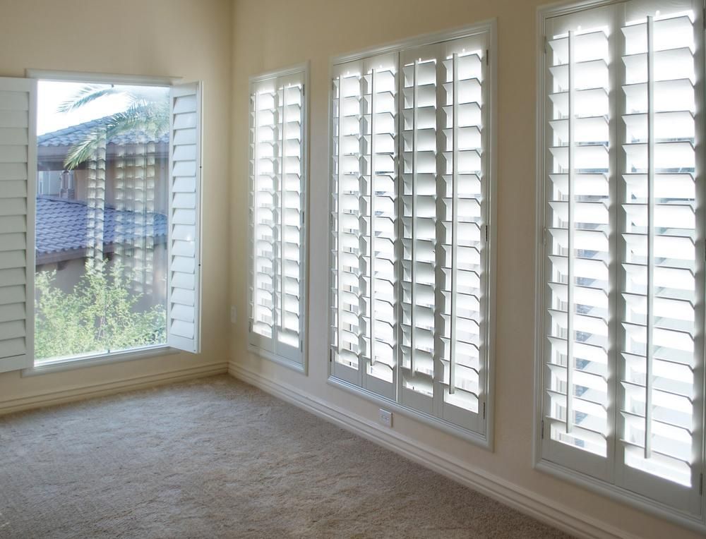 An Empty Room With White Shutters on the Windows — Design 2000 Blinds & Awnings In San Remo, NSW