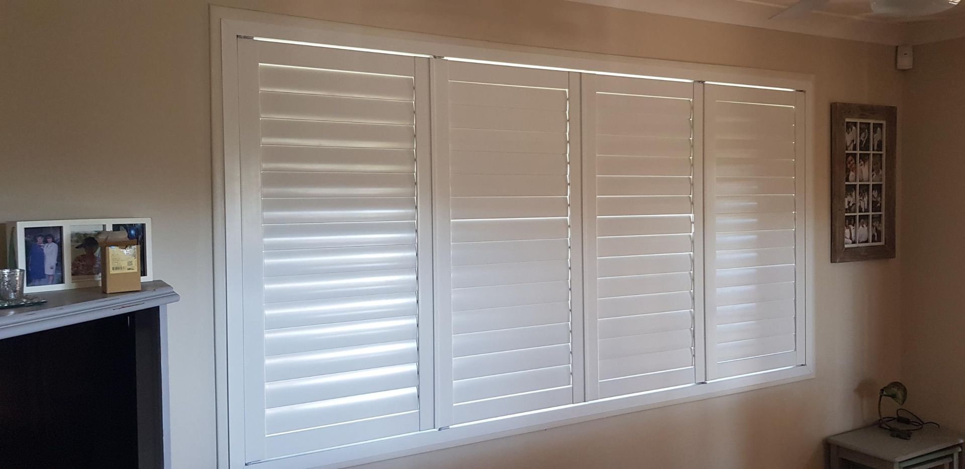 A Living Room With a Large Window With White Shutters on It — Design 2000 Blinds & Awnings In San Remo, NSW