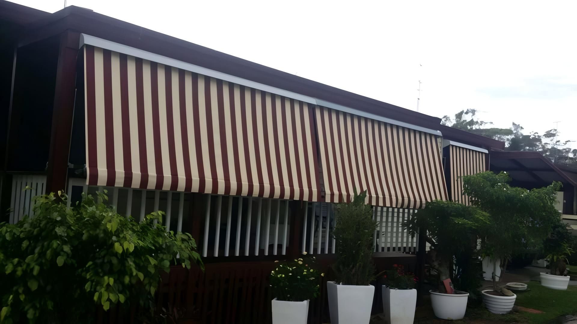 A House With a Striped Awning on the Side of It — Design 2000 Blinds & Awnings In San Remo, NSW