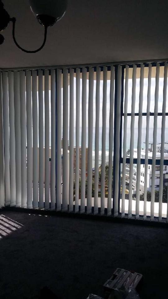 A Living Room With Vertical Blinds on the Windows and a View of the Ocean — Design 2000 Blinds & Awnings In San Remo, NSW