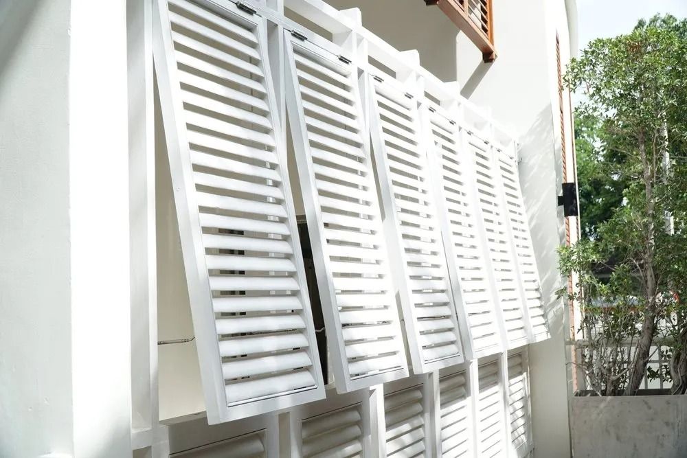 A Row of White Shutters on the Side of a Building — Design 2000 Blinds & Awnings In San Remo, NSW