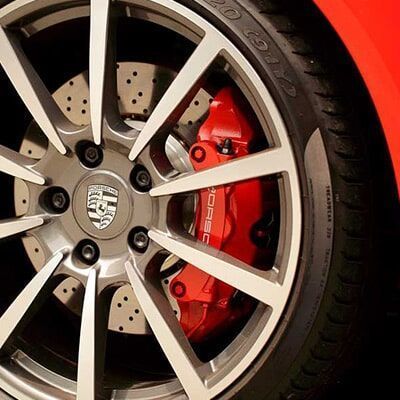 Un primer plano de una rueda Porsche con una pinza de freno roja