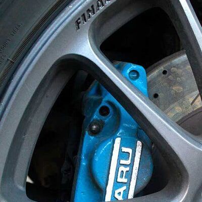 Un primer plano de una pinza de freno azul en una rueda de automóvil.
