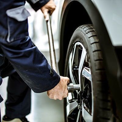 Un hombre está cambiando una llanta de un auto con una llave.