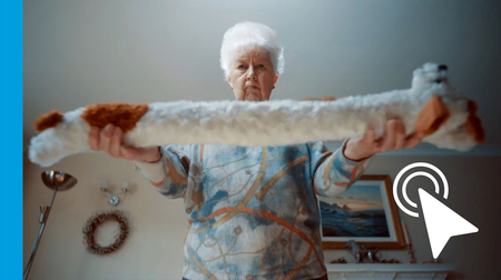 Woman holding a long white plush toy horizontally in a room