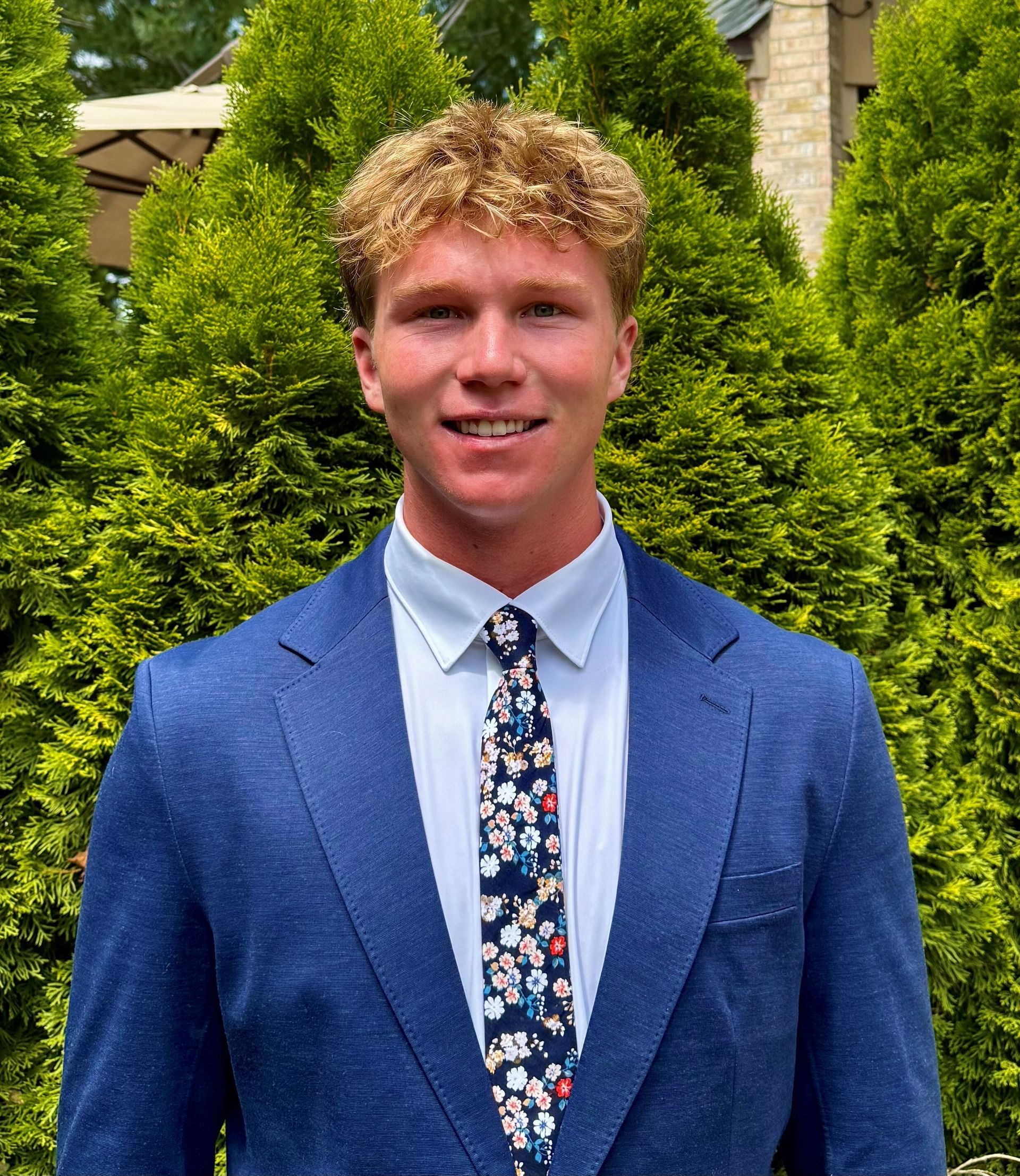 A woman with braids is wearing a blue jacket and smiling