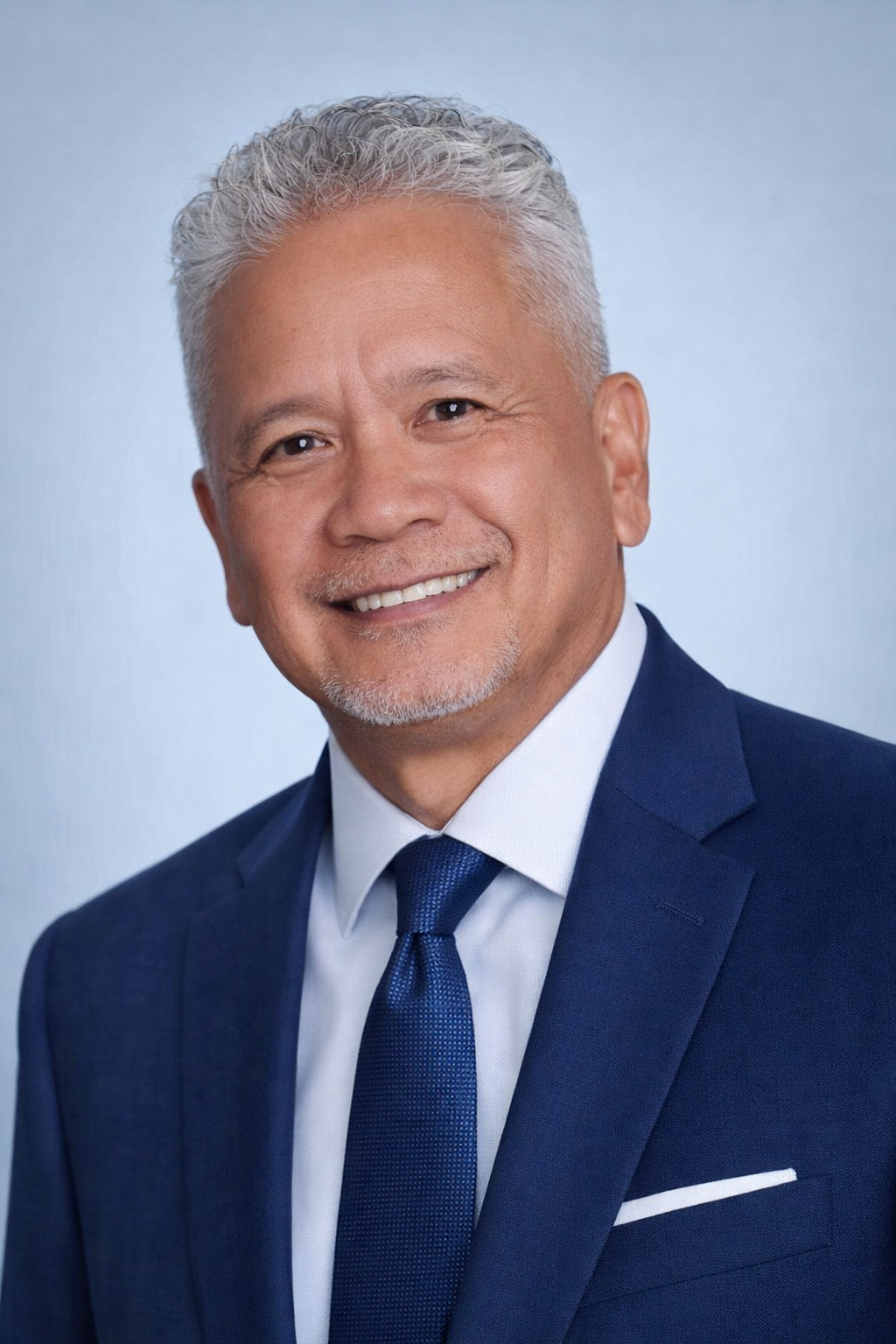 A woman with braids is wearing a blue jacket and smiling