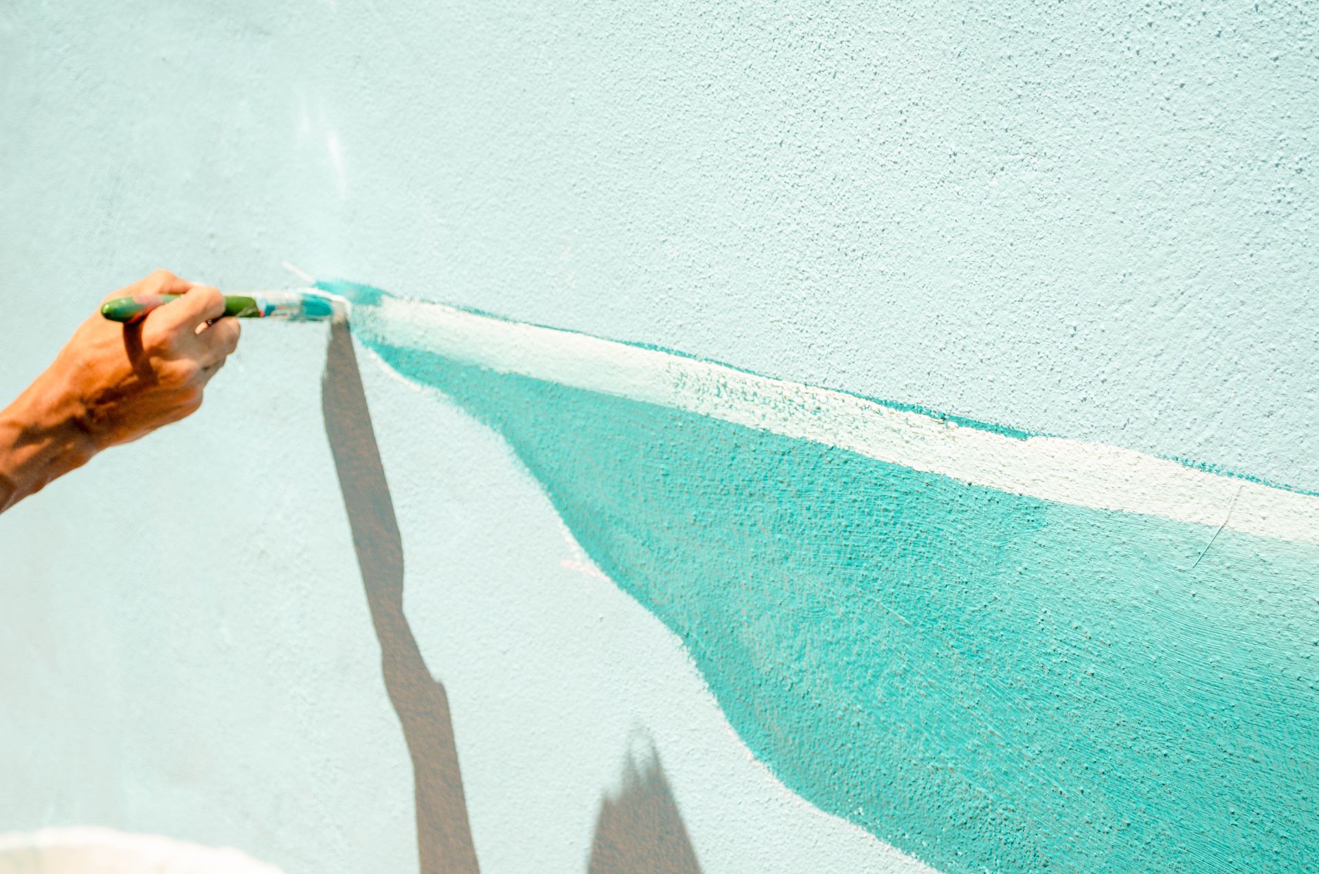 A person is painting a wall with a brush.