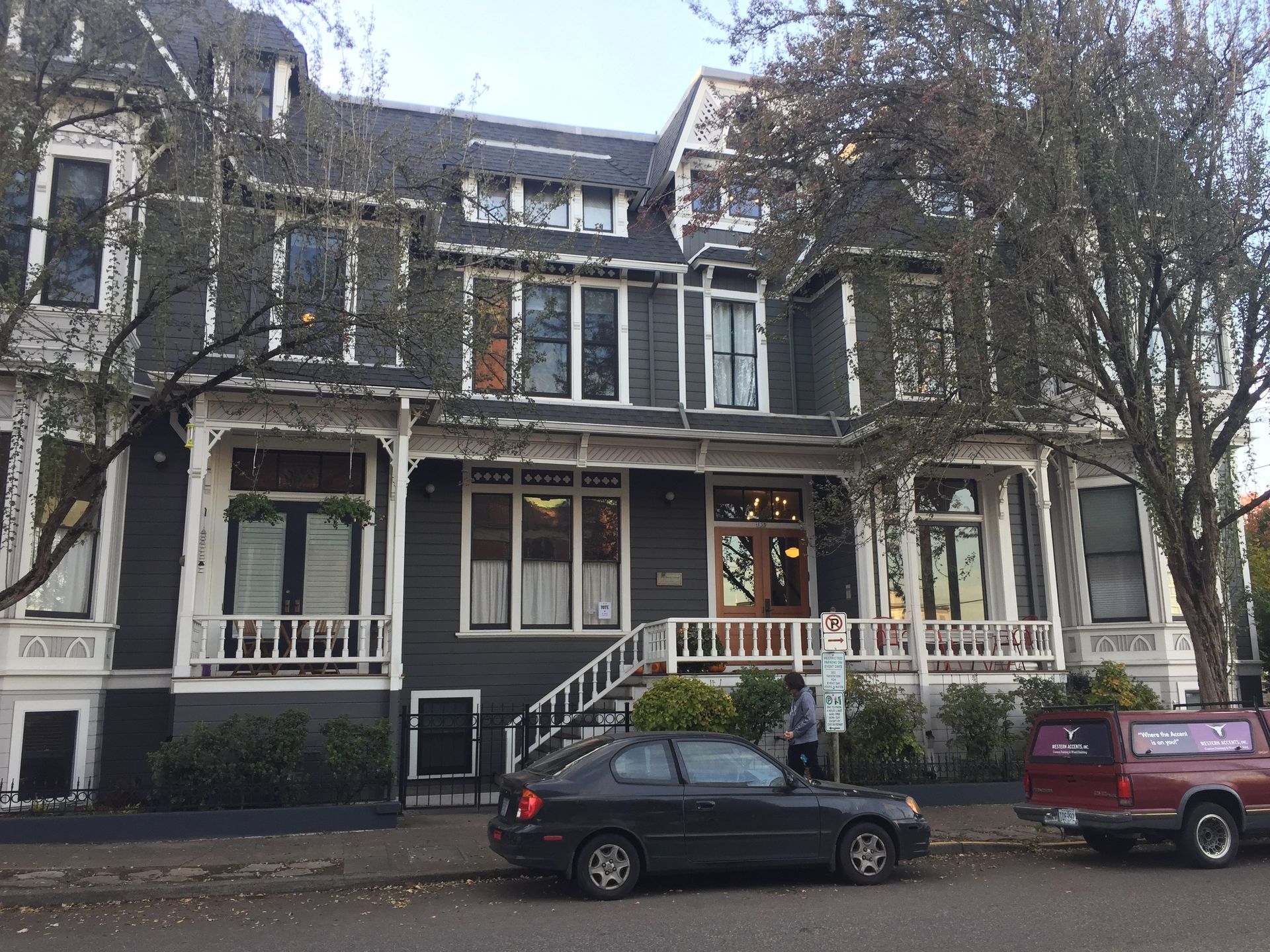 A black car is parked in front of a large house