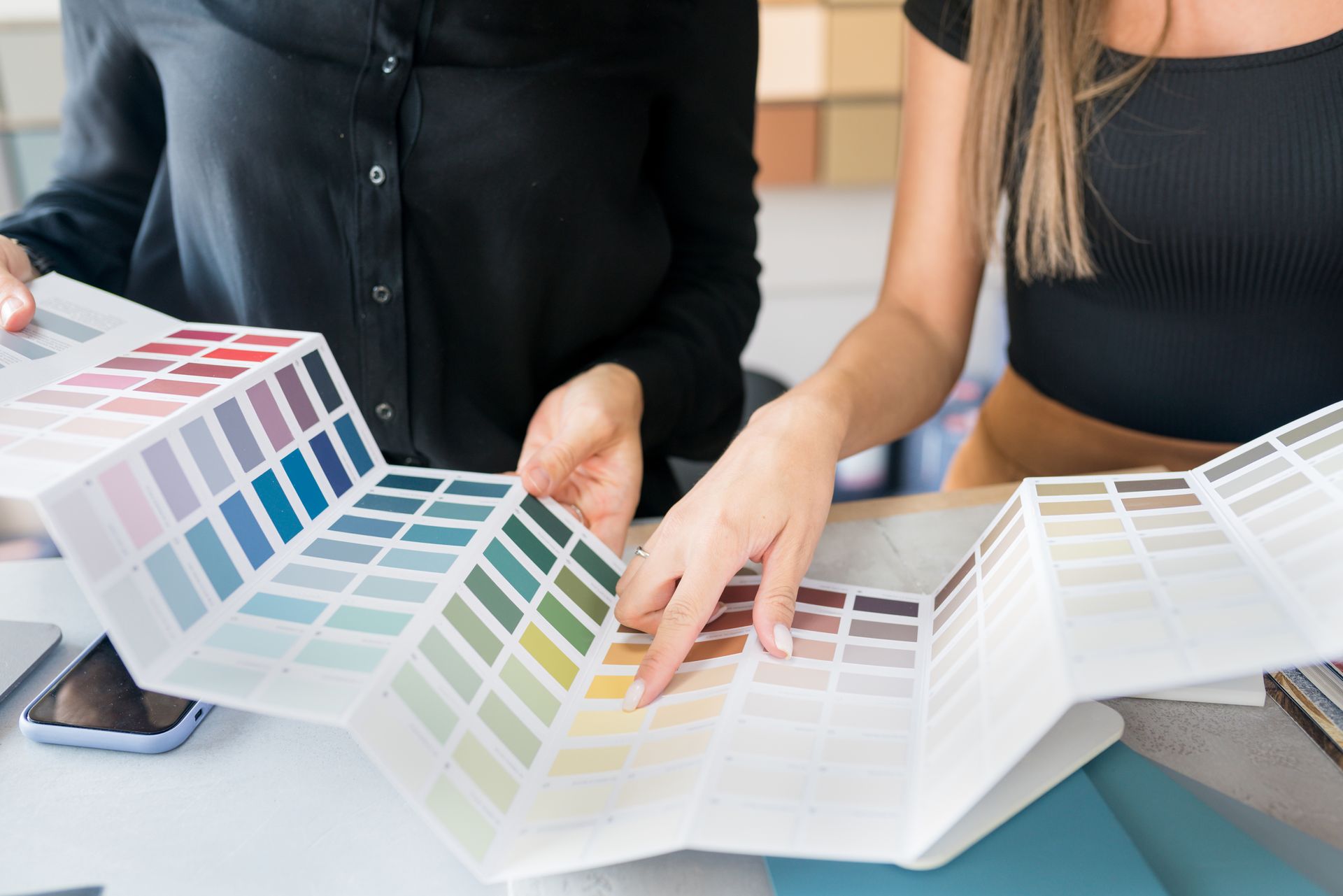Two women are looking at a color palette.
