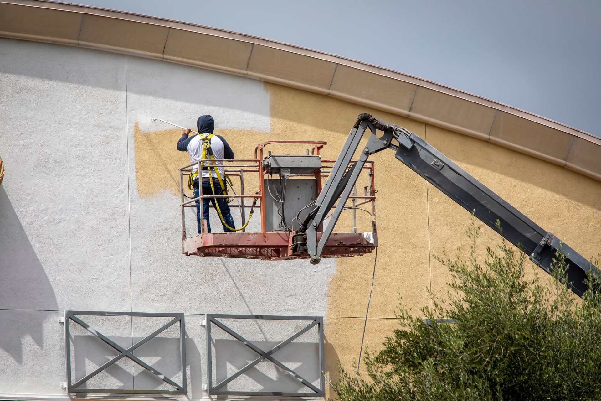 A man is painting a building with a crane.