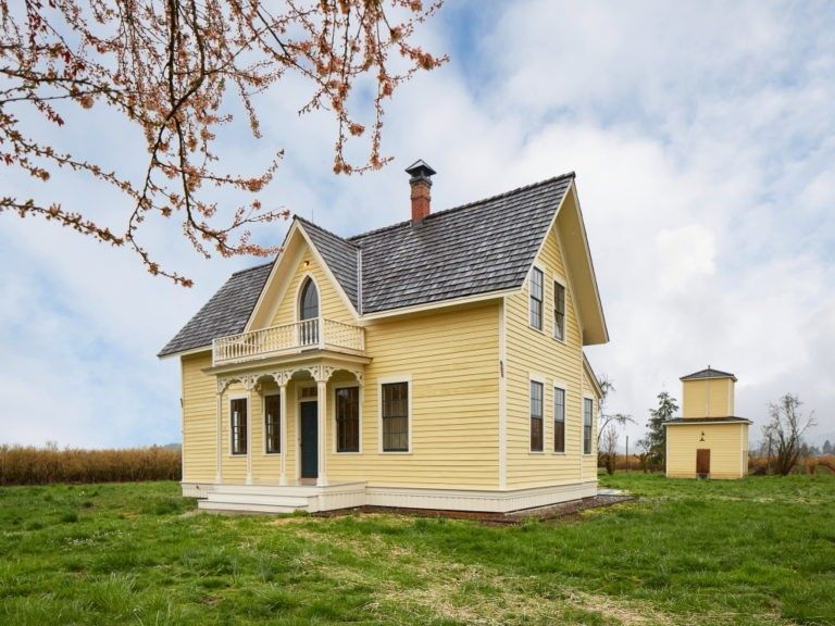 A yellow house sits in the middle of a grassy field