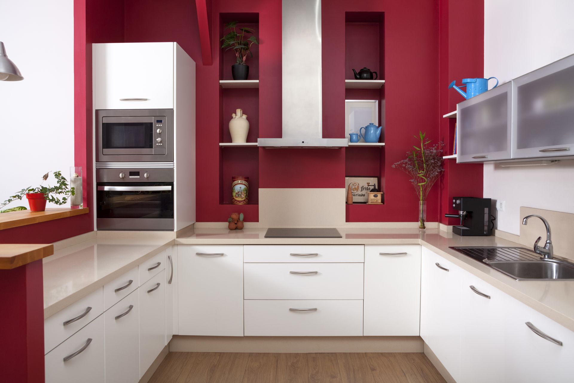A kitchen with white cabinets and red walls