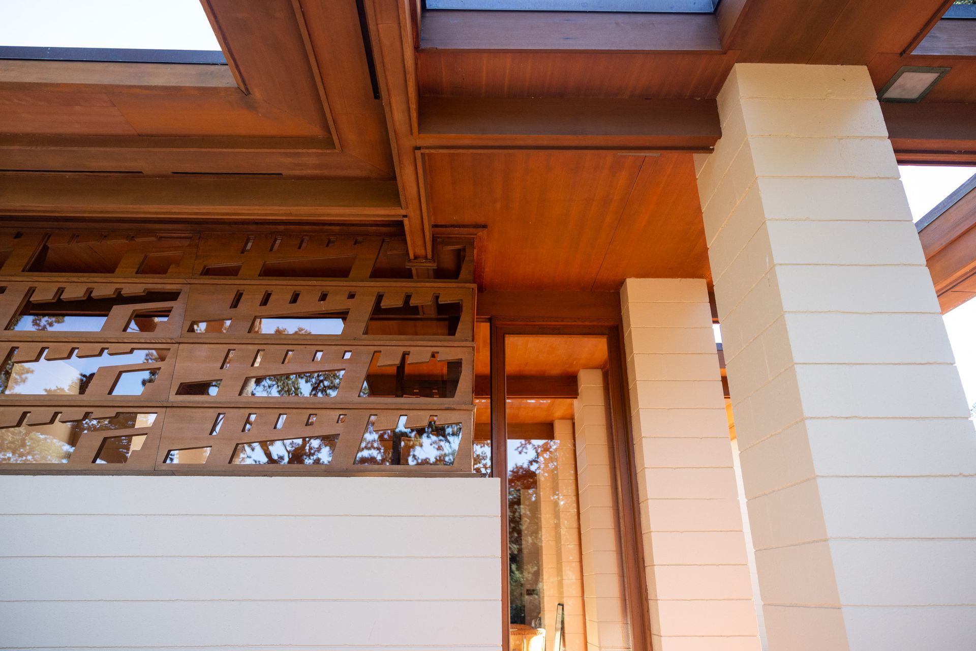 Beige and wood architectural detail: columns, ceiling beams, decorative screen.