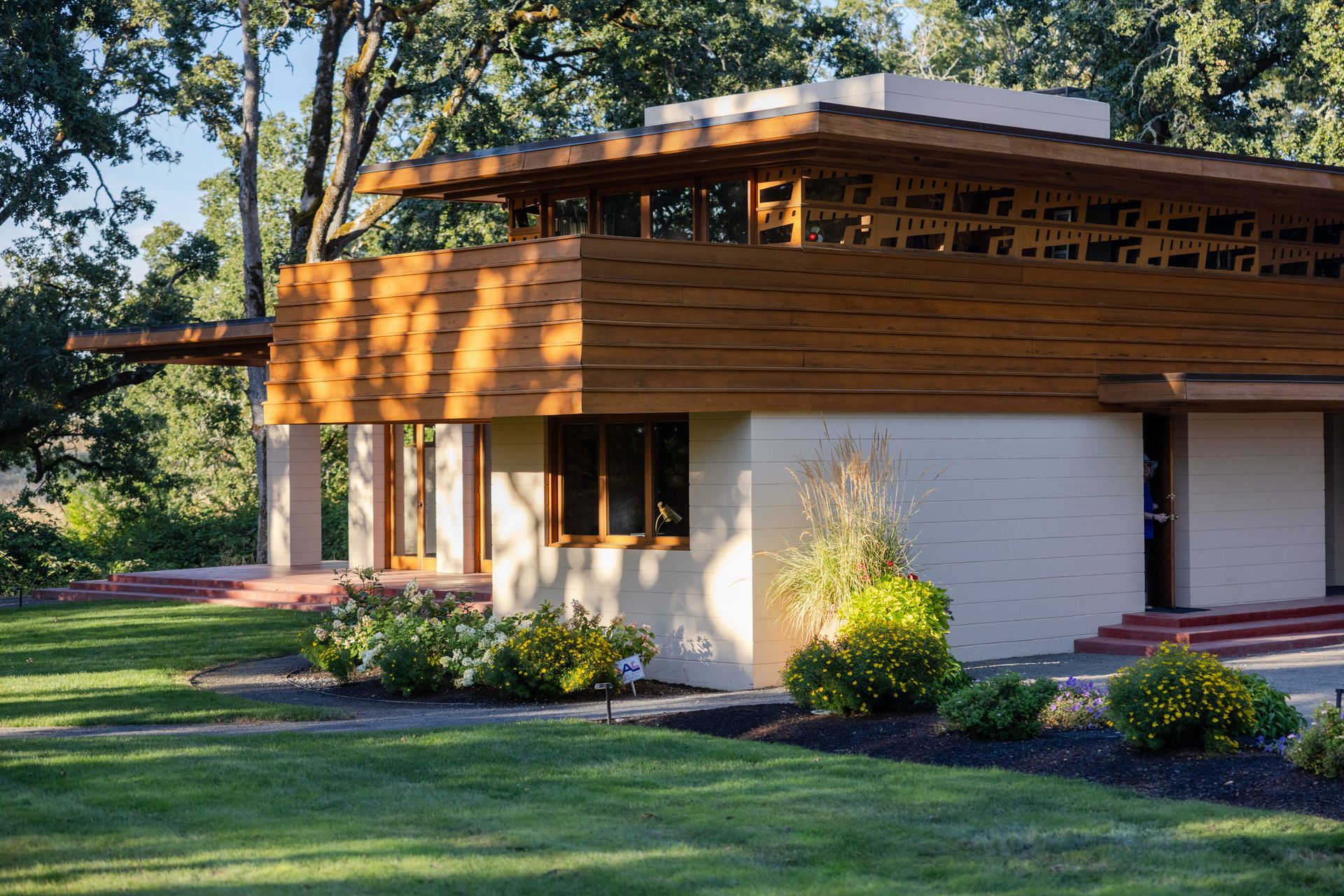 Low-angle view of a light-colored, modern house with wooden accents and a green lawn.