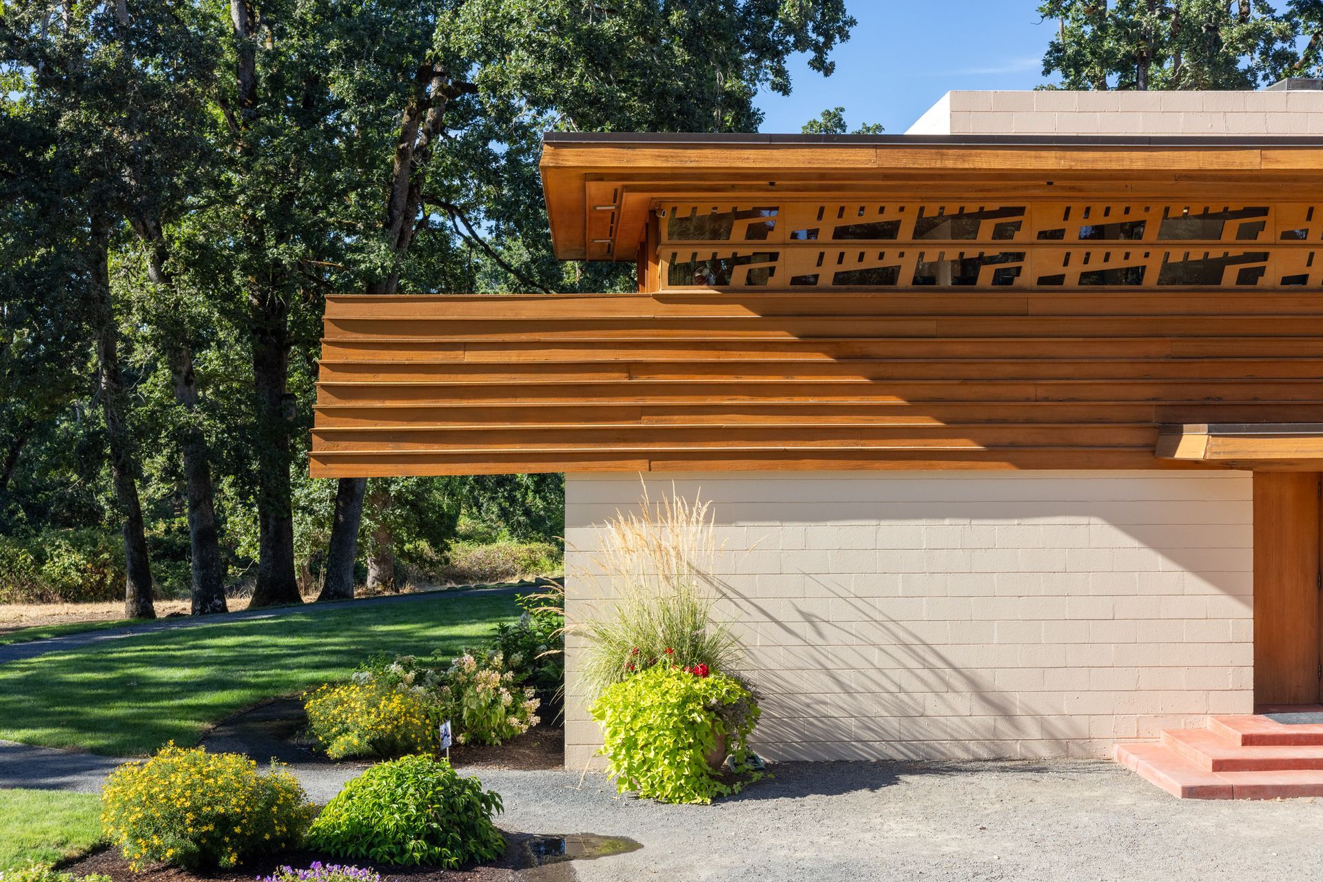 Close-up of a light-colored, mid-century modern style building with layered wooden roof and decorative cutouts.