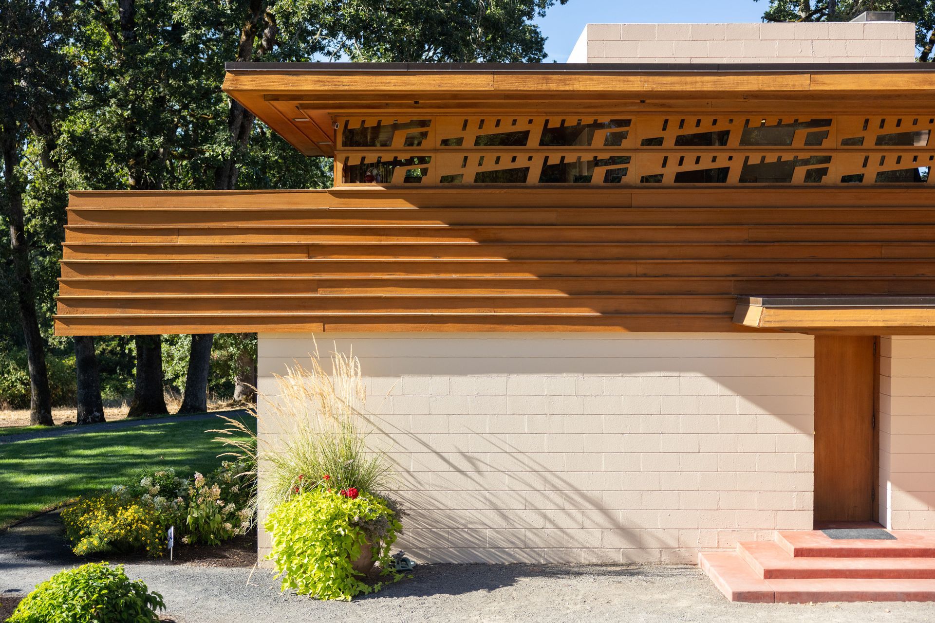 Beige and wood building exterior with decorative roof trim and front door.