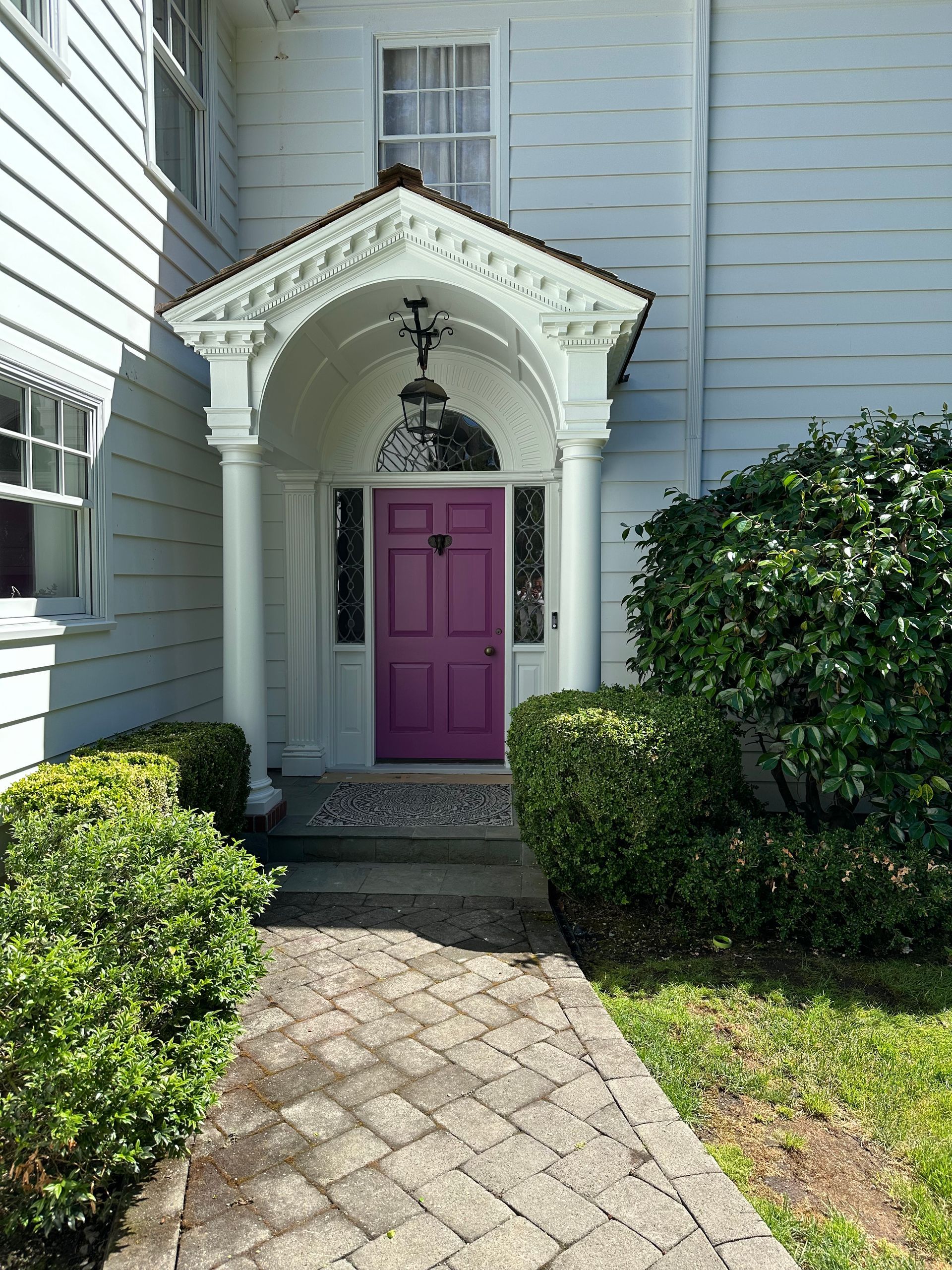 A white house with a purple door and a porch