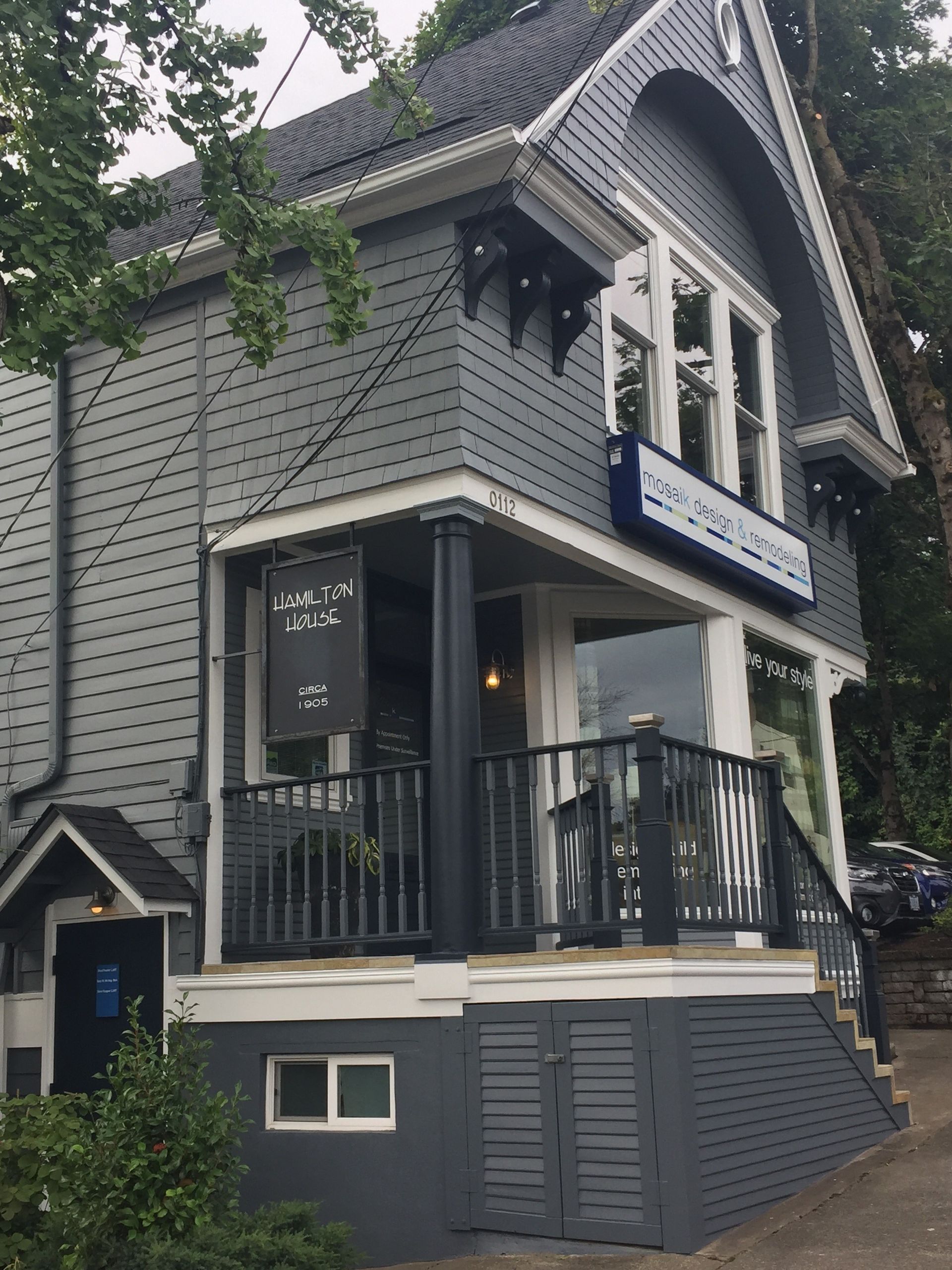 A large gray house with a balcony and stairs