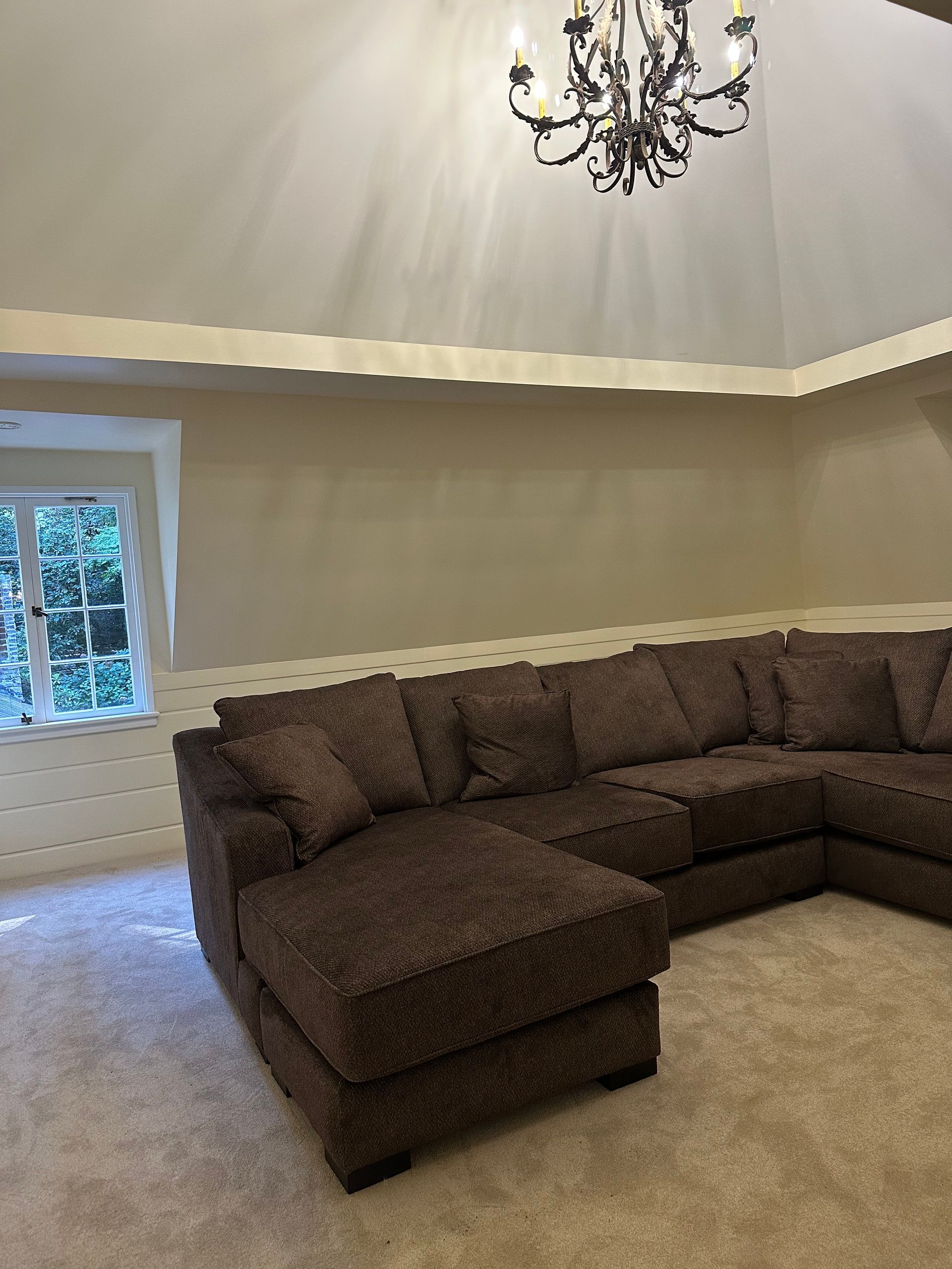A living room with a large sectional couch and a chandelier hanging from the ceiling.