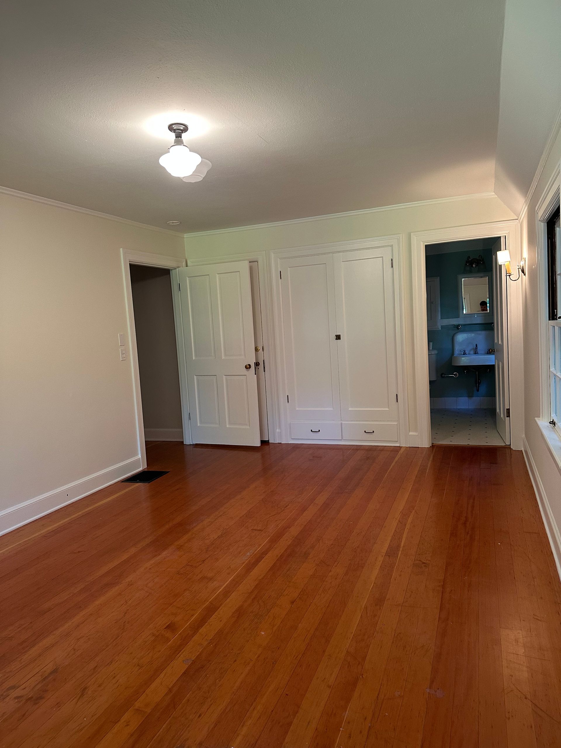 An empty room with hardwood floors and white walls.