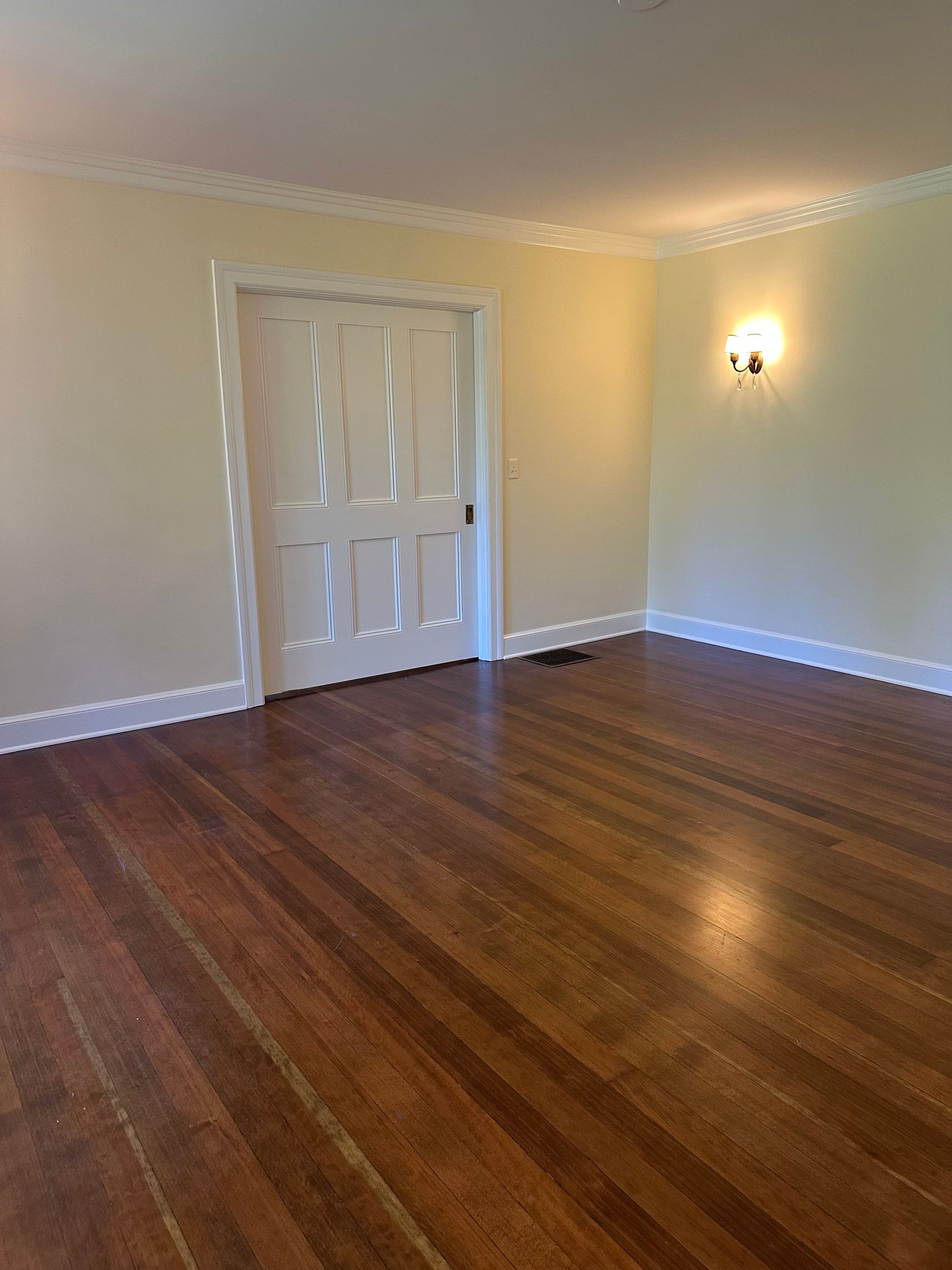 An empty living room with hardwood floors and white walls.