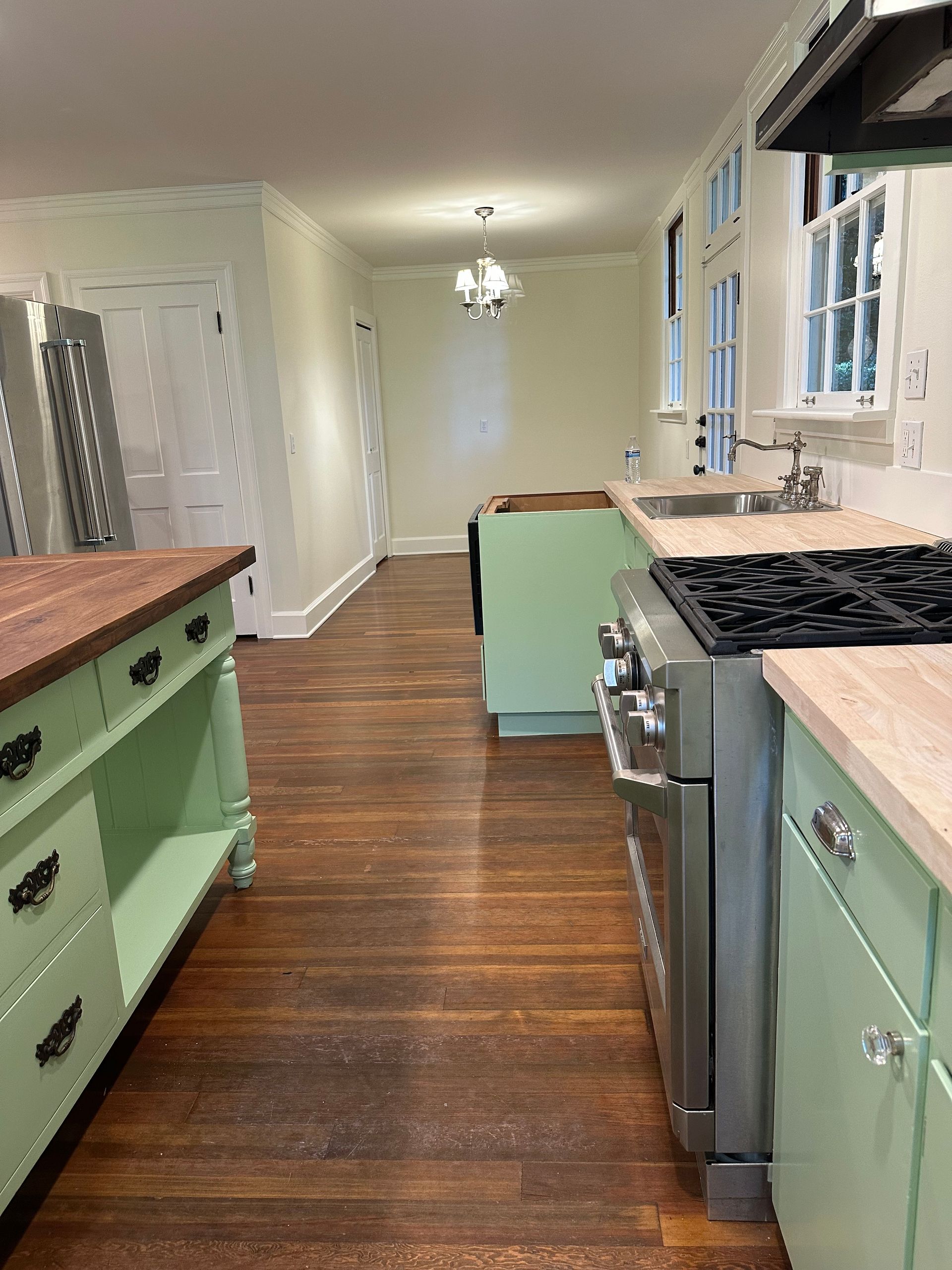 A kitchen with green cabinets , a stove and a sink.
