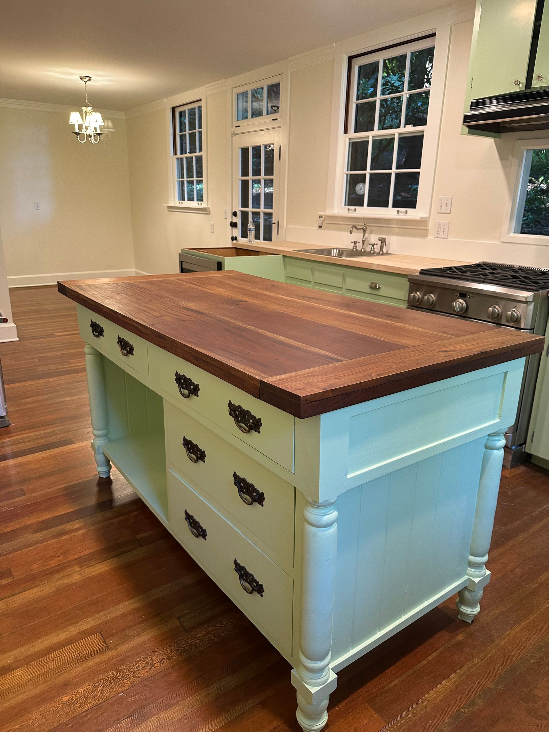 A kitchen with a large island with drawers and a wooden counter top.
