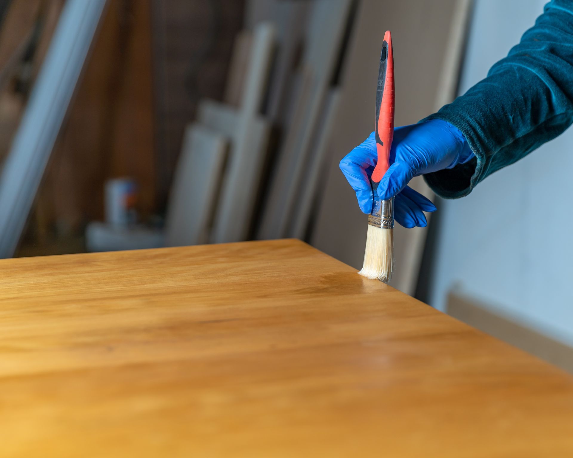 A person is painting a wooden table with a brush.