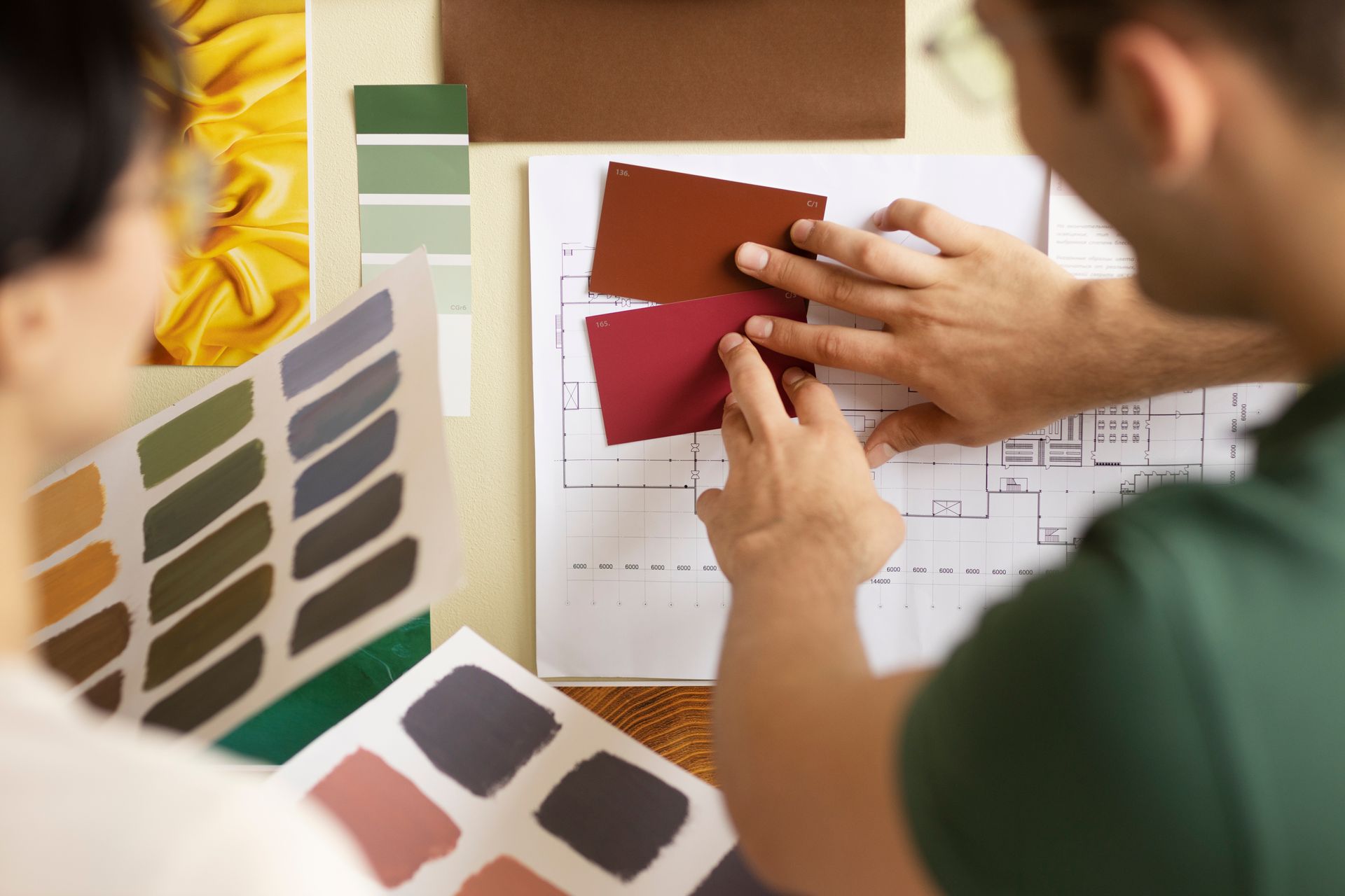 A man and a woman are looking at paint samples.