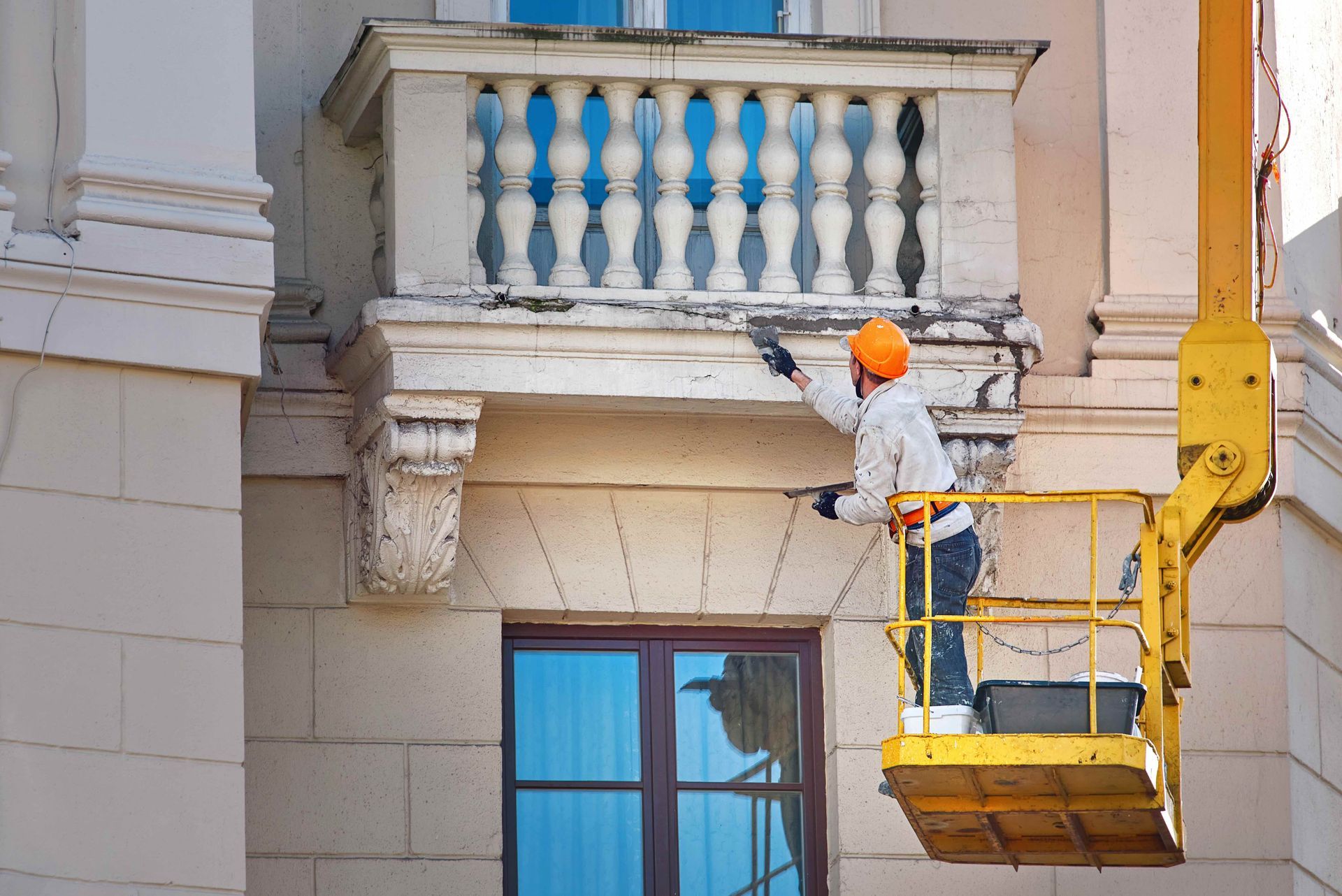 A man is painting a balcony on a building.