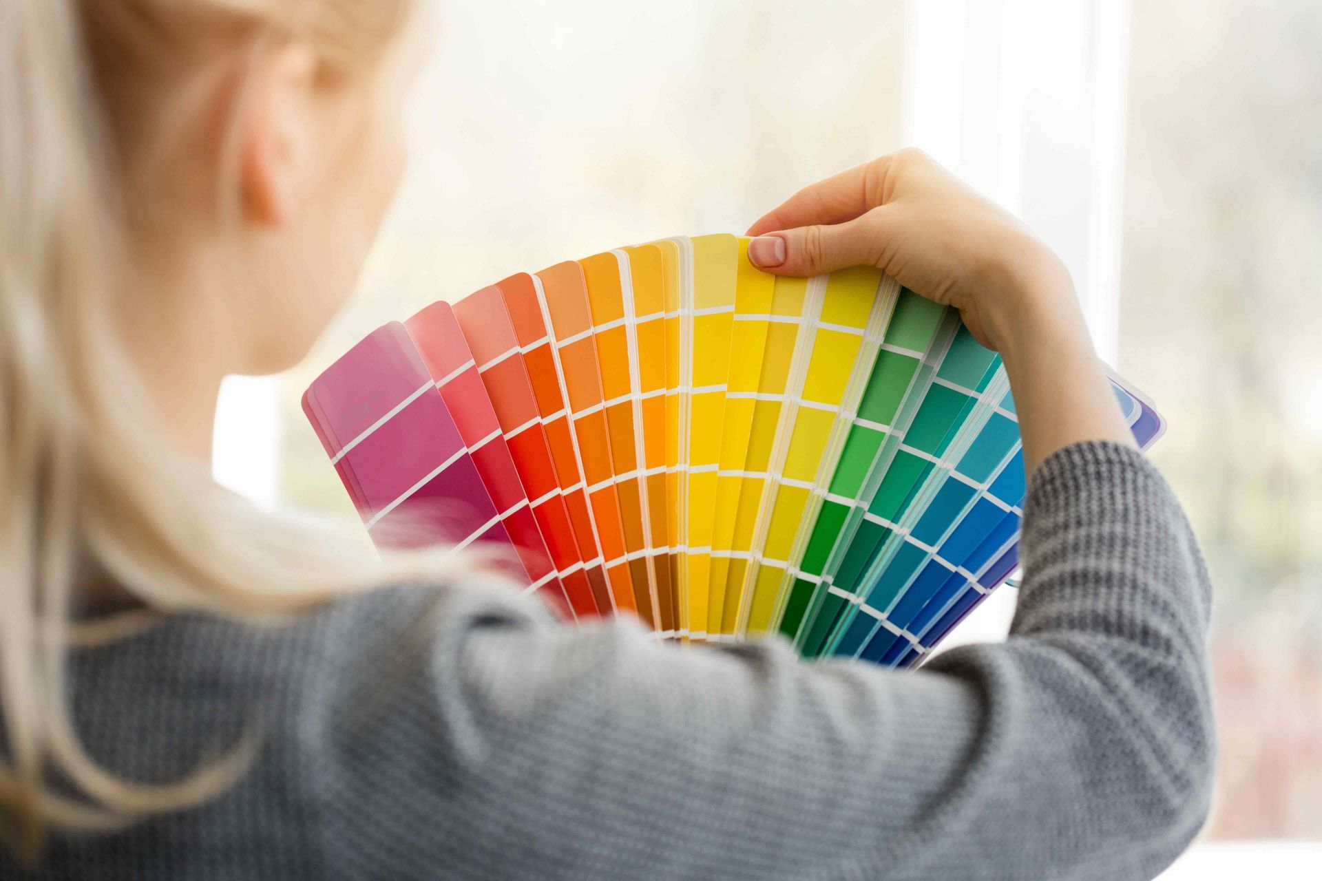 A woman is holding a fan of paint samples in her hands.