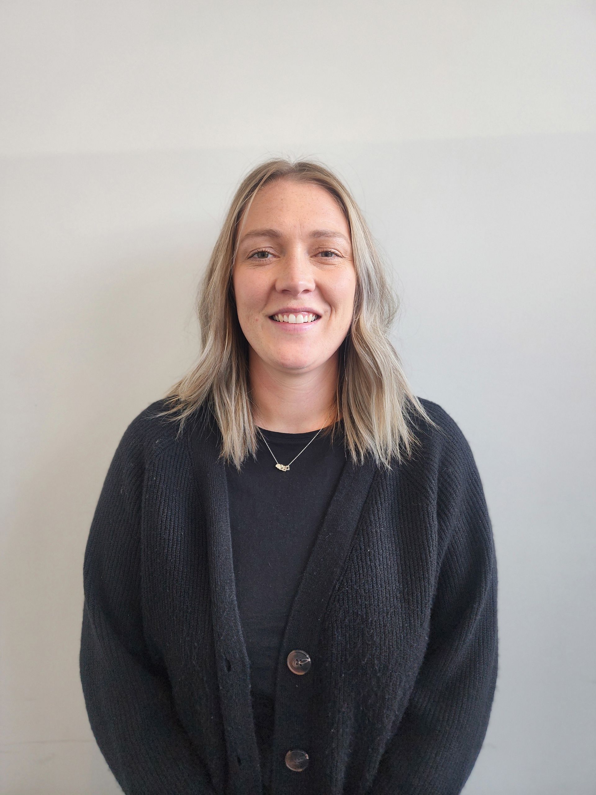 A woman in a black sweater is smiling for the camera.