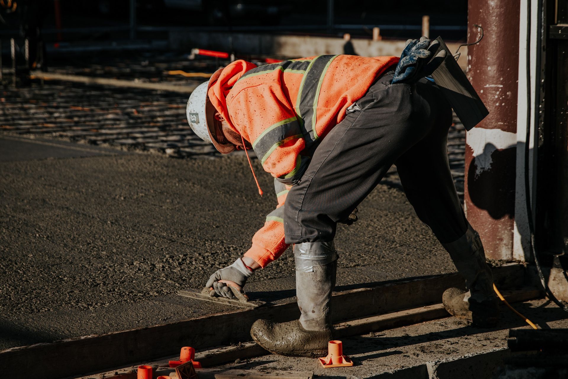 A construction worker is kneeling down on the ground.