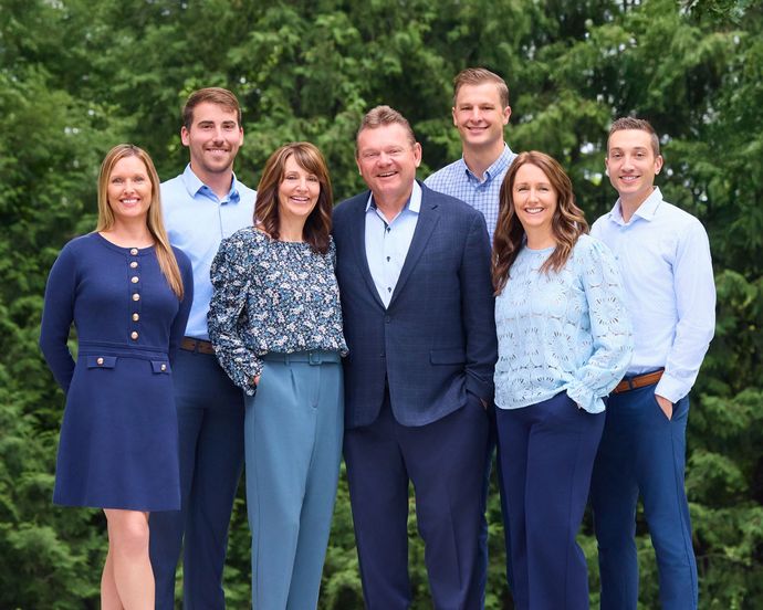 A group of people are posing for a picture in front of a framer retirement sign.