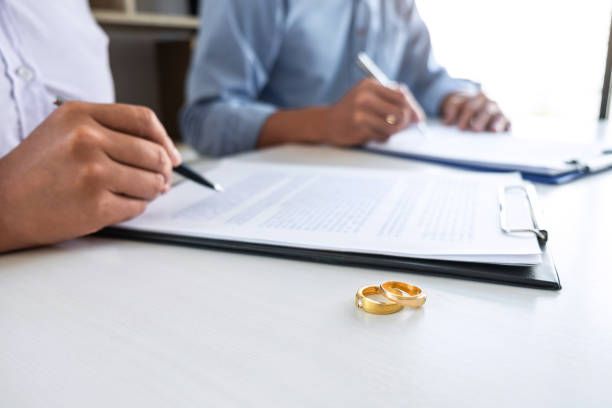 A couple of men are sitting at a table signing papers.