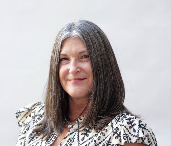 A black truck with patriotic decorations. A roof services company logo on the tailgate. A school bus is behind it.