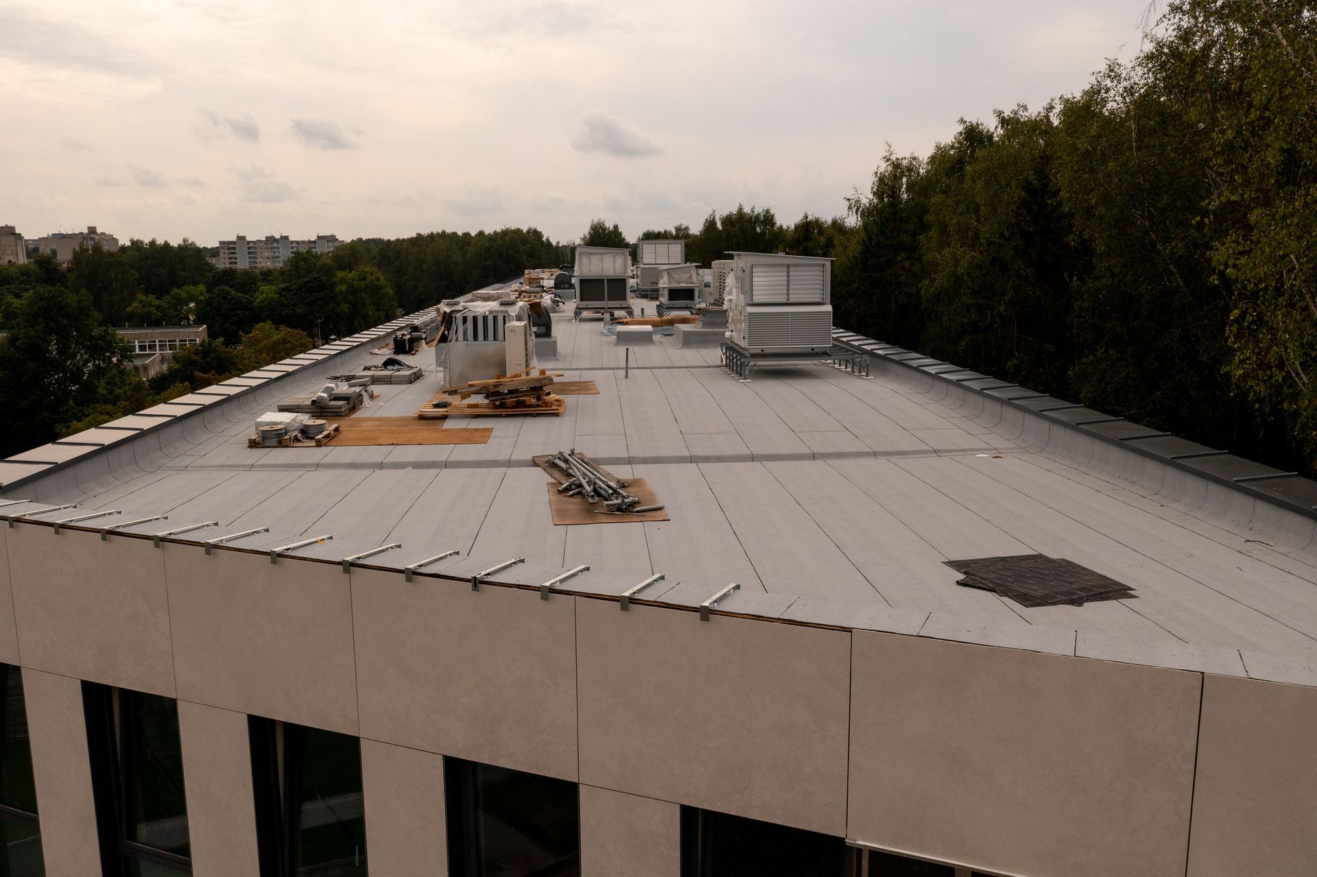 Rooftop with vents, in front of buildings. Brown roof, white and blue buildings, outdoors.