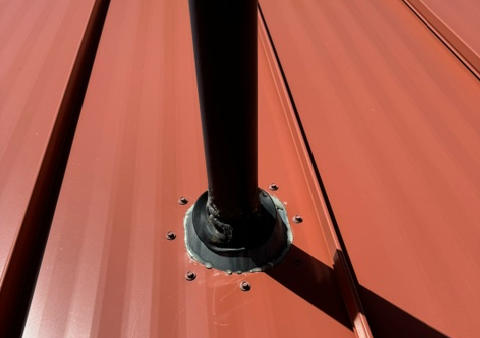 Person using a torch to install roofing material on a flat roof.