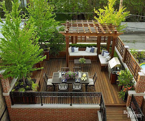 Wooden rooftop deck with a dining area, pergola seating, and lush greenery.