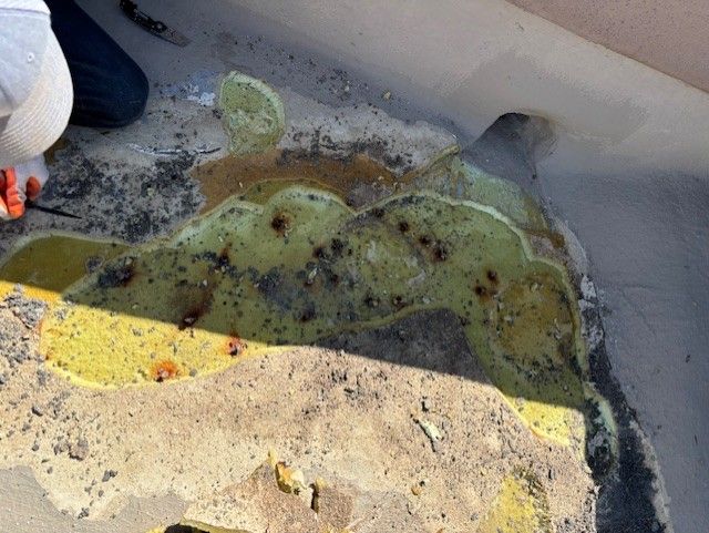 Damaged, yellow-green foam insulation on a roof; some debris around it. Someone is working on it.