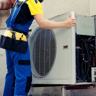 a man in blue overalls is working on an air conditioner