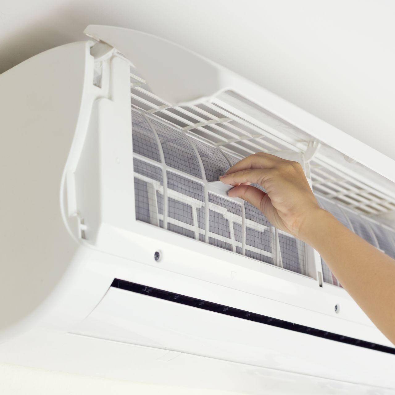 a person is cleaning the filter of an air conditioner