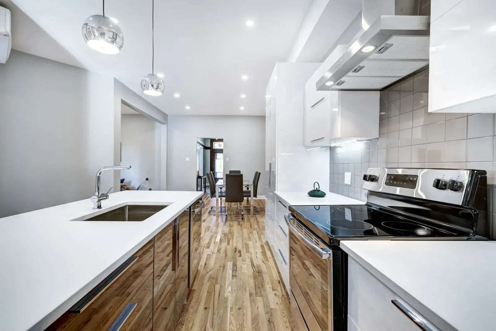 Modern kitchen with white countertops, wood cabinets, and stainless steel appliances.