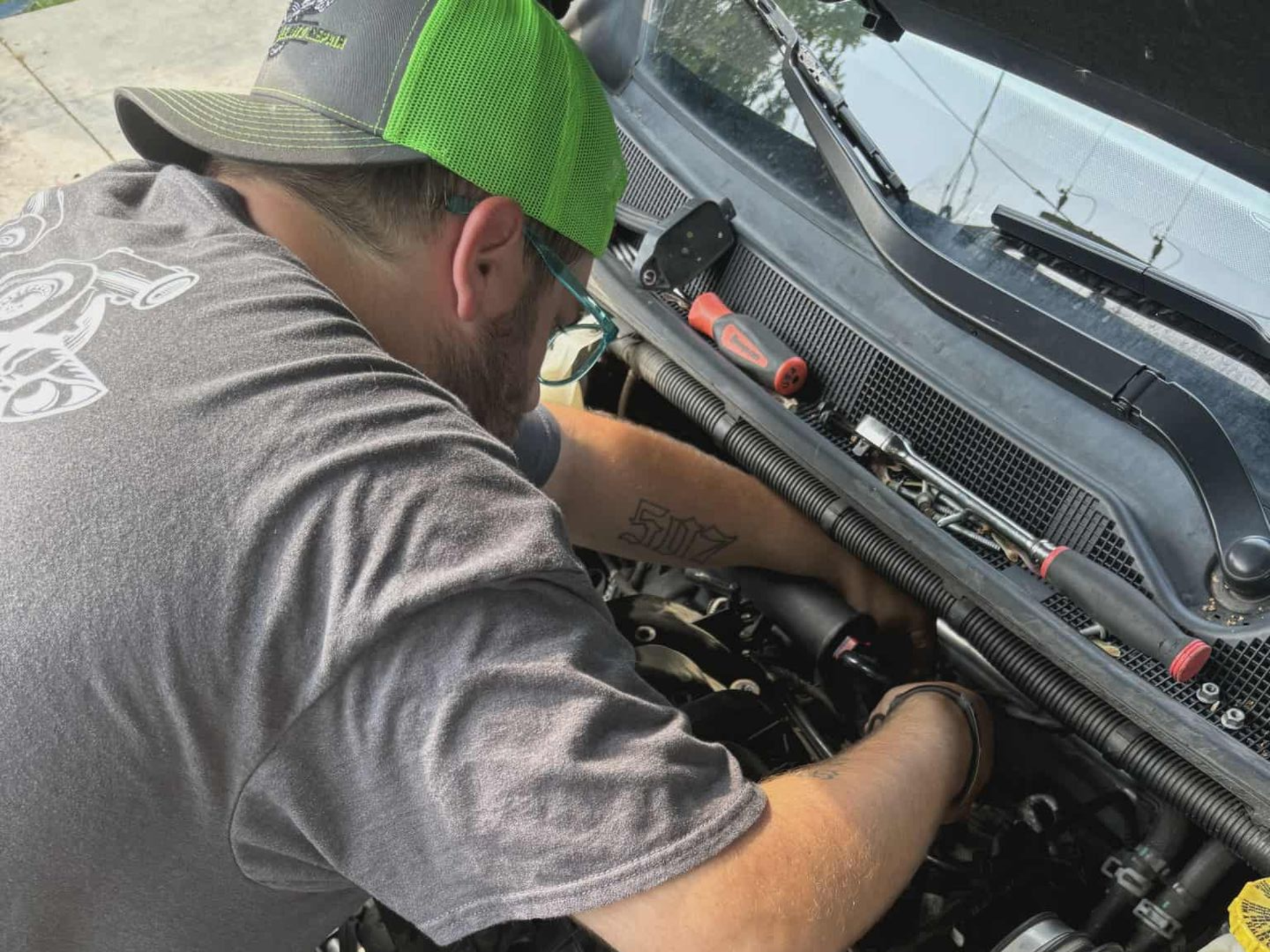 A row of tow trucks are parked in a grassy field.