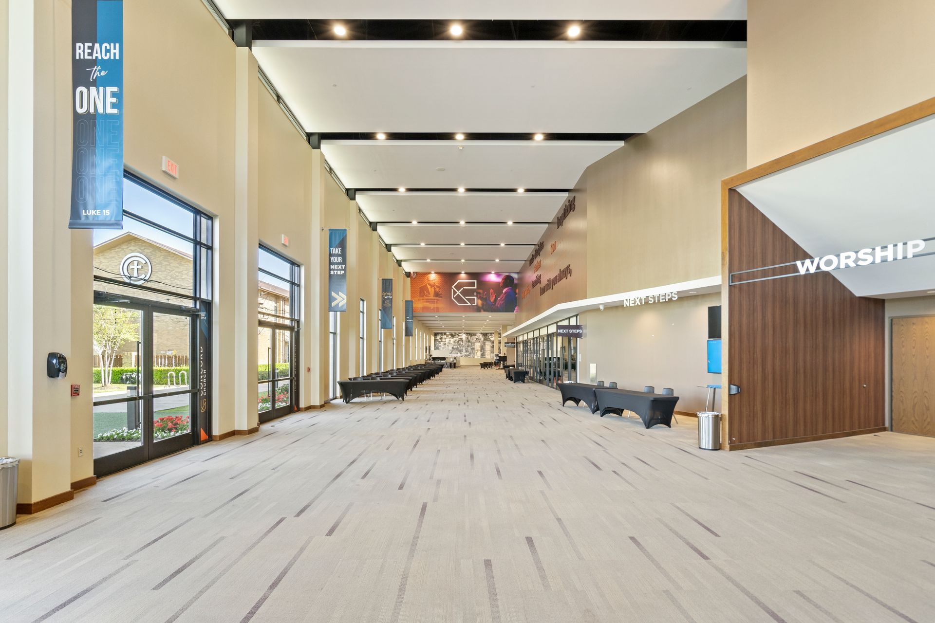 Hallway with benches, banners, and doorways. Sunlight streams in from exterior windows.