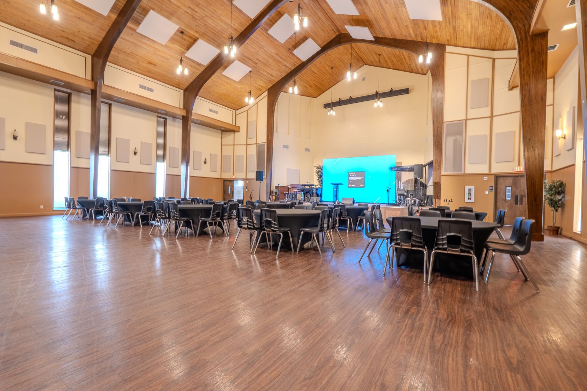 Large hall with tables and chairs set up for an event, stage in the back.
